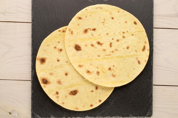 Two tasty tacos with slate stone on wooden table, macro, top view.