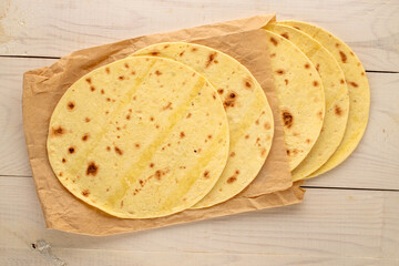 Several tasty tacos with paper bag on wooden table, macro, top view.