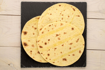 Several tasty tacos with slate stone on a wooden table, macro, top view.