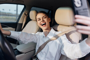 Woman taking a selfie in car a woman in the driver's seat of a vehicle holds her cell phone to capture a selfie, showcasing a moment of selfexpression and modern technology inside the automobile