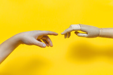 The hand of a robot,a golem,a mechanical man reaches out to the fingers of a real man.A parody of...