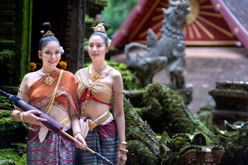 A beautiful Asian female tourist in a traditional Thai dress costume. The typical of local Buddhists is Wat Pha Lat Temple a famous tourist attraction in Chiang Mai Thailand.