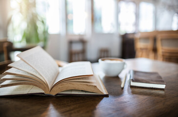 An open book for reading and relaxing with coffee drink and diary book for writing memoirs on wooden table in cafe