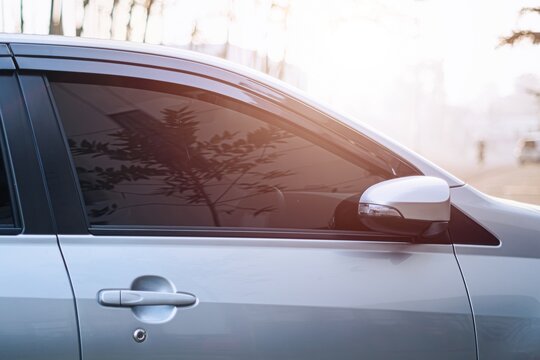 A car with tinted window reflects reddish sunlight and bokeh background