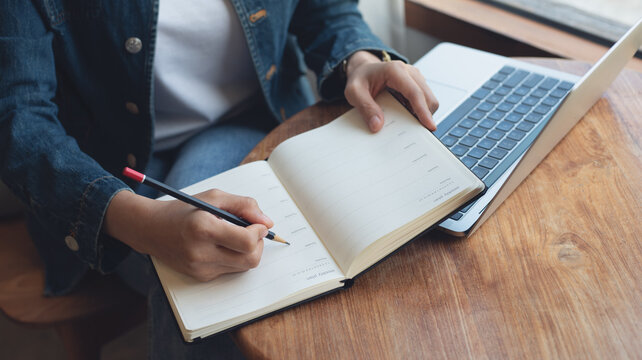 2025 Event planner timetable agenda plan on schedule event. Business woman checking weekly planner, taking note on calendar notebook on office table. Calendar event plan, work planning