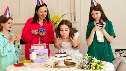 Birthday girl in white dress blows out candles