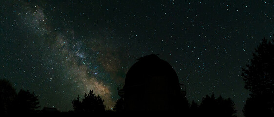 Night sky with stars and the silhouette of observatory