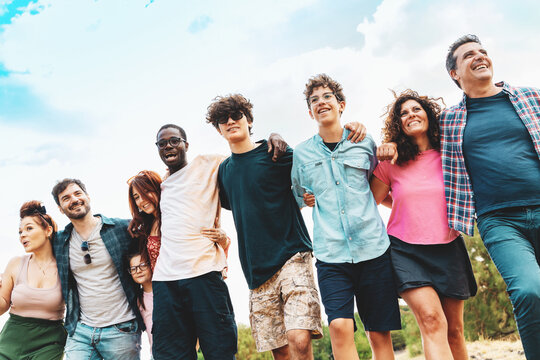 Multigenerational diverse group of friends and family smiling outdoors, unity concept