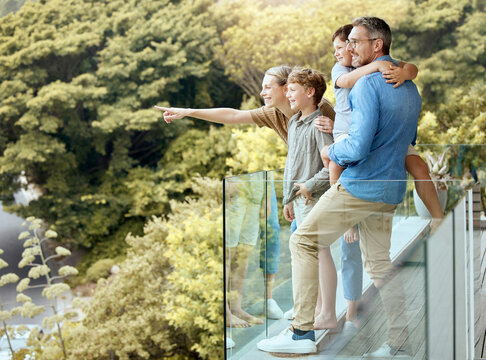 Happy, family and and pointing on balcony, parents and bonding with children, smile and love in home. Outdoor, mom and dad with kids, hand and glasses for man, summer and woman in property and house - Powered by Adobe