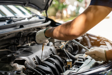 Fototapeta premium Close-up of Car mechanic noting repair parts during open car hood engine repair unrecognisable man wearing gray glove inspecting car engine and interior 