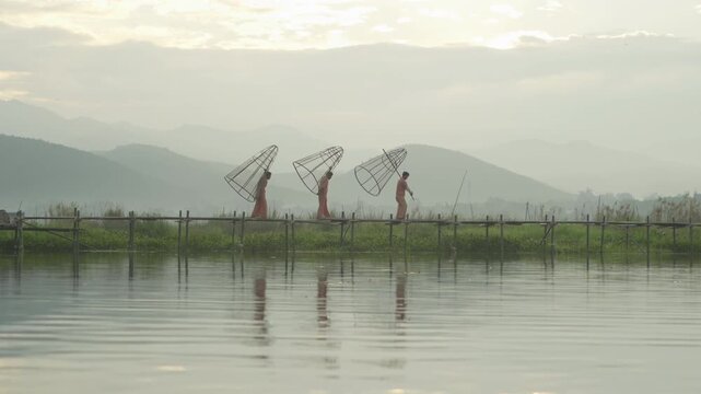 Burmese fisherman casting or throwing a net for catching freshwater fish in Unle lake, natural river in Asia in Myanmar. People lifestyle.
