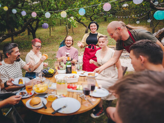 Young people friends celebrating around a table in garden in countryside