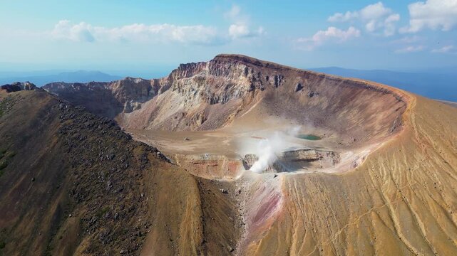 Mt Meakan, Hokkaido: Dramatic aerial drone footage of the crater of the active Meakan volcano in the Akan Mashu national park in Hokkaido in summer in Japan. Shot with a backward and tilt up motion. 