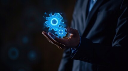 A businessman in elegant suit holding a set of blue digital hologram gears or cogwheels above his hand.