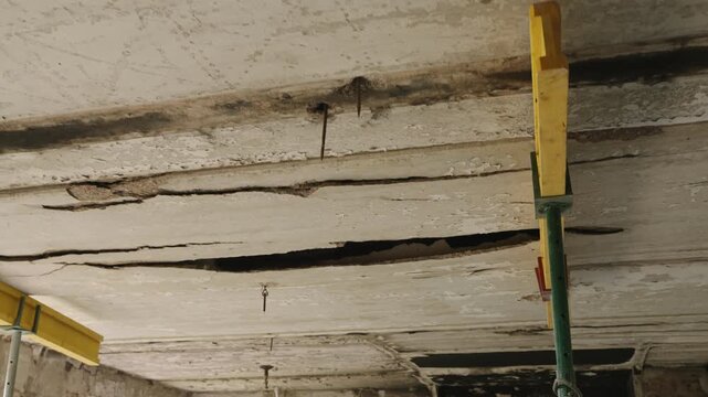Burnt apartment in Mariupol shows war impact. Cracked ceiling, damaged walls in residential building. Devastating effects of shelling, visible destruction, concrete debris. Urban decay documented.