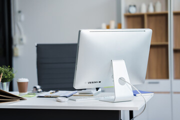 An empty work desk is shown, devoid of any person. The desk is neatly organized with office supplies, a computer, and paperwork, indicating a professional workspace ready for use.