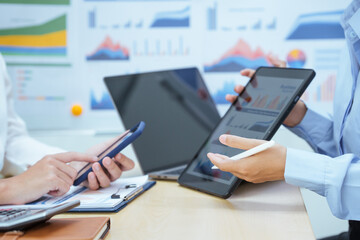 Two young Asian businesswomen sit at a table, engaged in a meeting.examine graphs and discuss capital investment strategies, showcasing their expertise and collaborative approach to business growth.