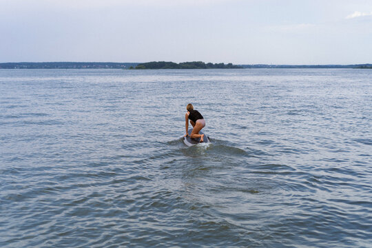 A woman rides a hydrofoil on a lake.