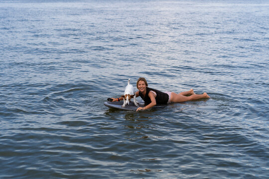 A woman rides a hydrofoil with dog.