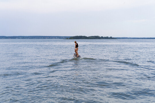 A woman rides a hydrofoil on a lake.