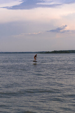 A woman rides a hydrofoil on a lake.