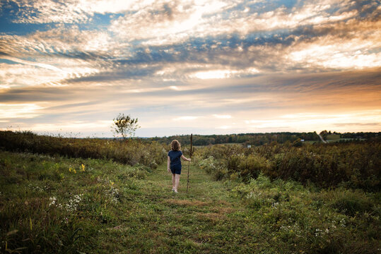 Young girl walking down green path at sunset