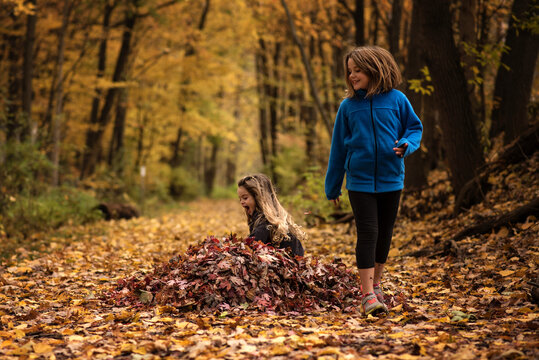 Happy young sisters playing in colorful leaves