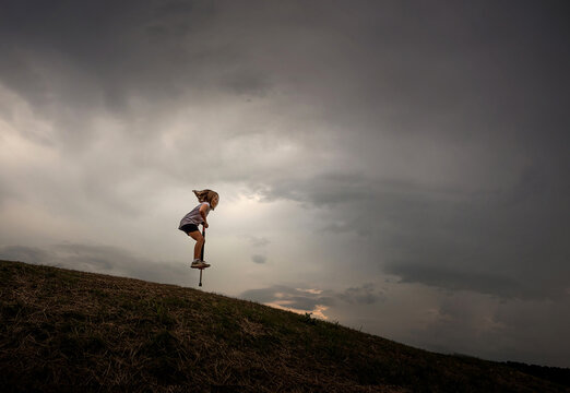 Young girl hopping down hill on pogo stick