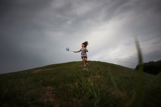 Young girl running down hill with bug net