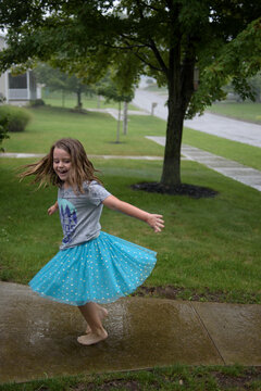 Young girl playing in summer rain shower