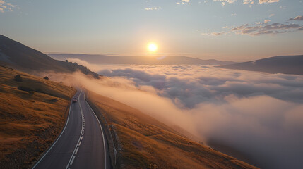 Photo of A Car drive on the highest road of the mountain. left running lane There is fog floating below the road. The sun is behind.
