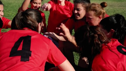 Excited Female Soccer Team in Pre-Game Huddle, A joyful female soccer team in red jerseys huddles together, showing enthusiasm and team spirit before a game.