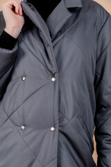 Close-Up of Grey Quilted Coat. Vertical Photo. Close-up vertical photo of a grey quilted coat with diamond patterns, showing details of the fabric and buttons