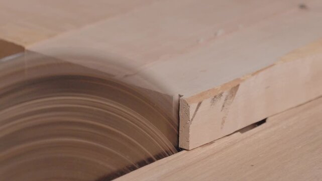 A man carpenter uses circular saw as cutting tool for trimming wooden planks. The milling of board blocks in a carpentry factory or workshop. Close up. Shooting mode no face.