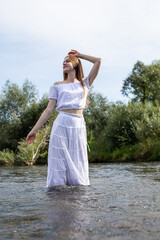 Graceful figure of a girl. A woman in a white dress in the water. Woman's wet dress. Bathe in the...