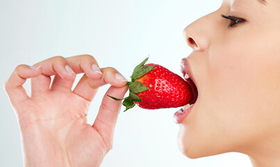 Woman, health and eating strawberry in studio for skincare, wellness or vitamin C. Female...