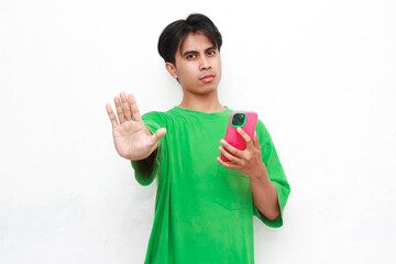 An Indonesian man ( Asia ) wearing a green shirt, holding a smartphone, with his hand raised in a...