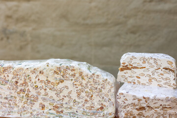 French dessert nougat with honey, almonds and nuts at a market in front of a beige house wall