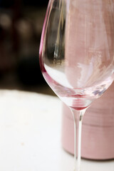 Wine glass with rest of red wine on a white table with ceramic water bottle in the background