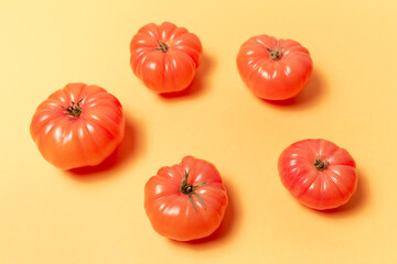 Close-up of pink tomatoes on background of pastel yellow color.