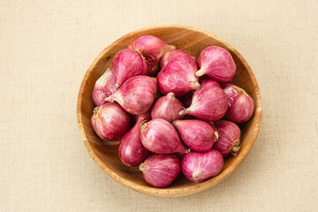 Fresh shallots on wooden bowl, food ingredients
