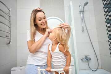 Young mother and daughter making curlers in a bathroom