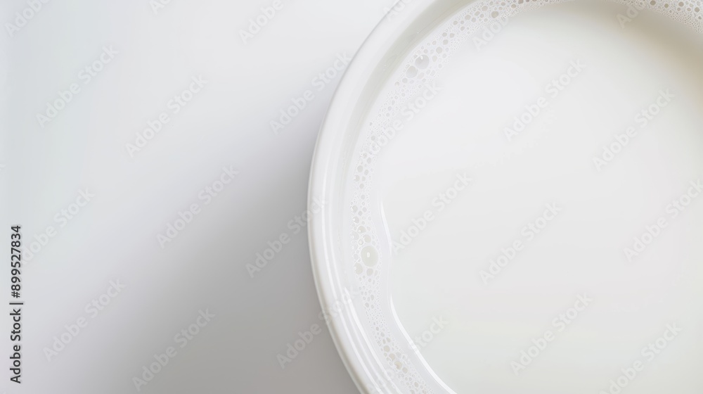 Poster fresh milk in a white bowl on a clean background, creating bubbles. top view emphasizes its nutritio