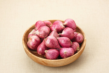 Fresh shallots on wooden bowl, food ingredients
