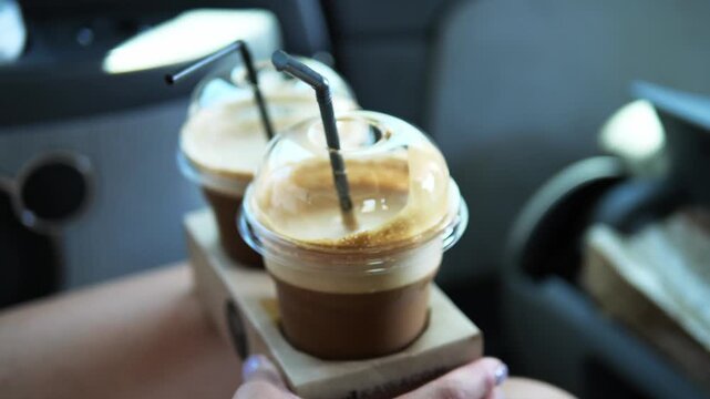 Two cold coffees in plastic cups with a black straw inside, stand in cup holders. These cold coffees are ideal for a hot day, offering a refreshing and chilled beverage experience.Refreshing effect