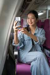 Asian traveler women using smartphone to taking photo of sky view through the windows on cabins...