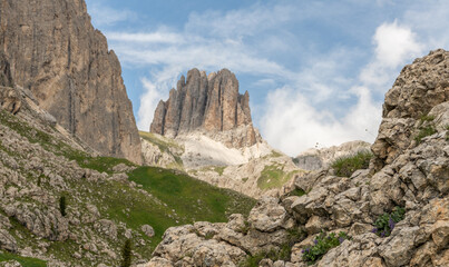 Naklejka premium Italian Dolomites during a cloudy summer day. Fresh alpine meadow in foreground, impressive Dolomites mountains in background. Wonderful hiking spot, amazing hiking area in Italy. Outdoor activities.