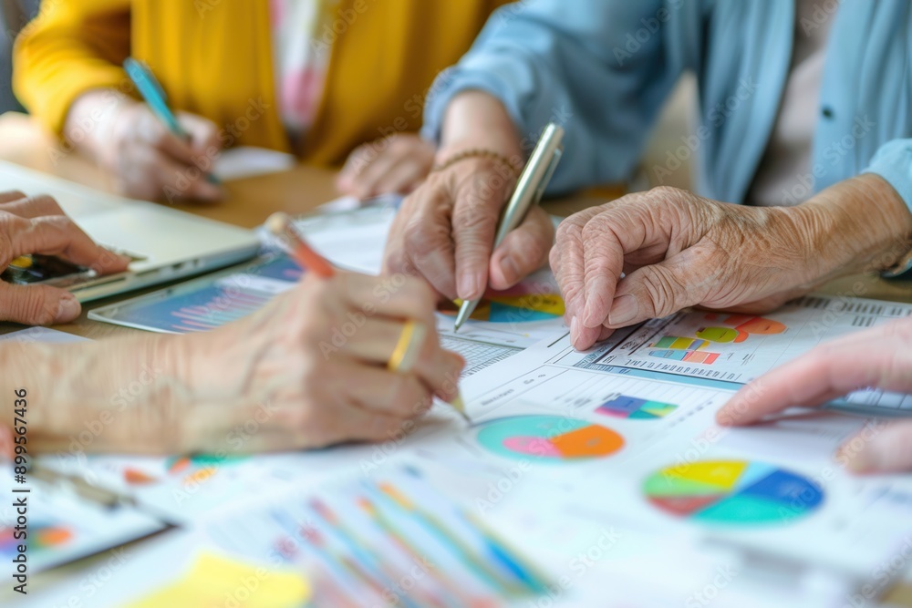 Poster a group of elderly people collaborates at a table, analyzing various charts and graphs, discussing i