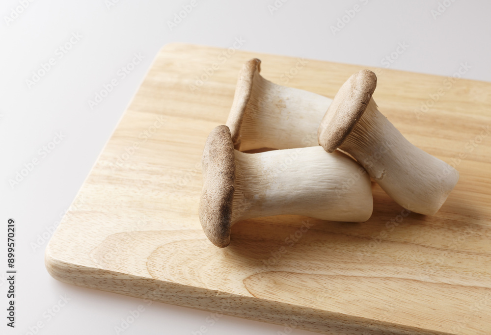 Wall mural Close-up of three fresh King Oyster Mushroom on wood cutting board, South Korea
