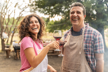 Happy couple enjoying wine while barbecuing outdoors, lifestyle and romance concept